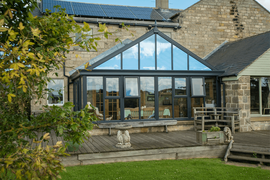 glass roof gable dark navy grey aluminium and uPVC conservatory though shrubbery