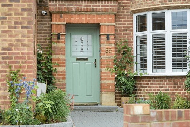 green composite door exterior next to white uPVC bay window with blinds