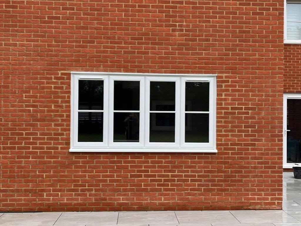 White uPVC casement window with four panels set in a red brick wall.